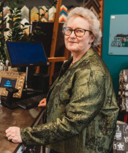 Jeanette achter de kassa bij Kreawood glimlachend naar de camera in de winkel in Harderwijk